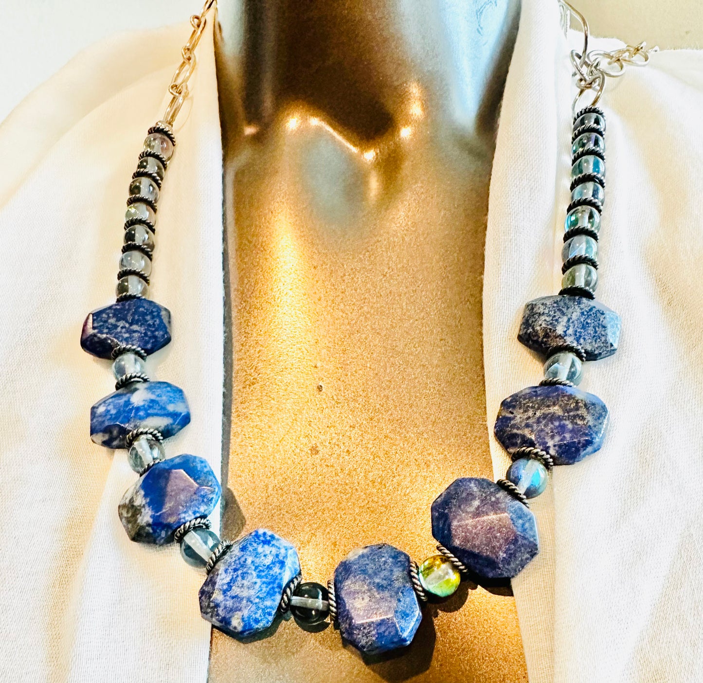 The pieces are crafted with care and feature a combination of gemstones, sterling silver, sodalite, and opalite.
The adjustable necklace measures between 14 to 24 in