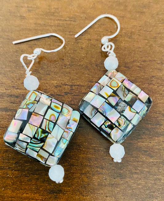 Crafted from seashell and moonstone, these statement earrings boast an understated yet weightless quality, alluding to the size of a quarter. Pendanting from a ste